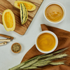 Two bowls of squash puree with cut squash, spices, and herbs on a wooden surface.