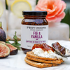 Jar of Provisions Fig & Vanilla Jam with crackers and figs on a marble surface.