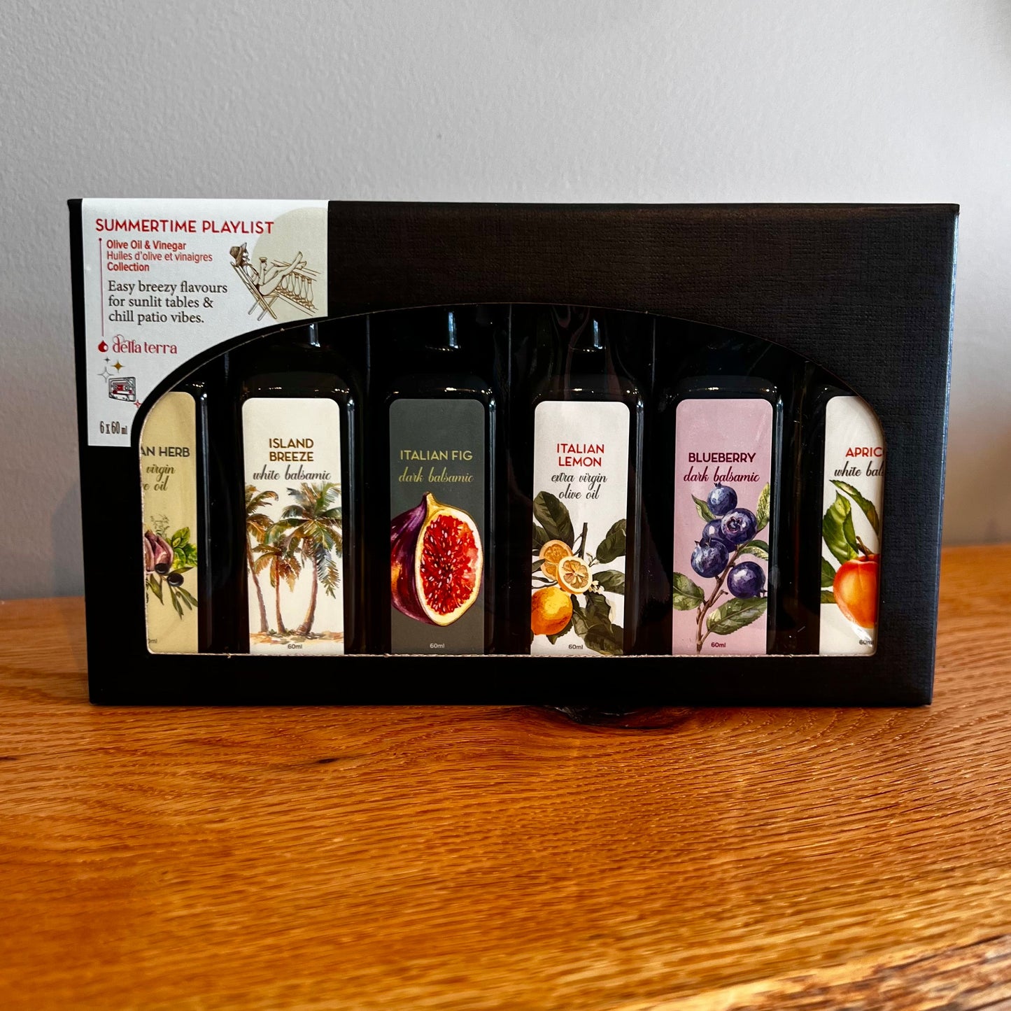 Set of small bottles with labels in a black box on a wooden surface. This set is the Summertime Playlist 2026 Tasting Flight